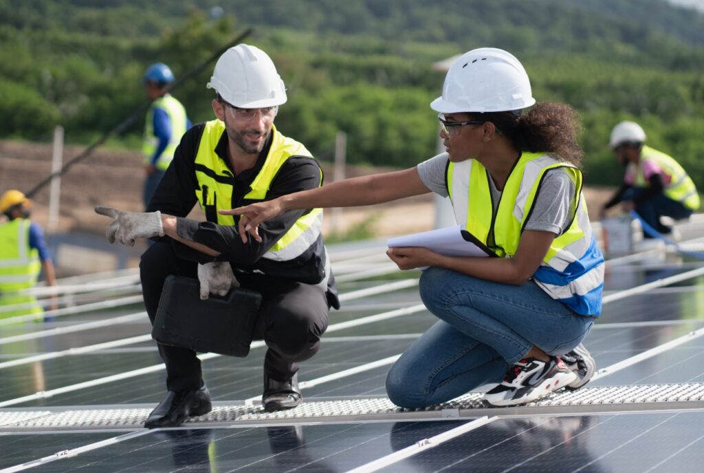 A solar worker points out something on the panels she's installing to a coworker