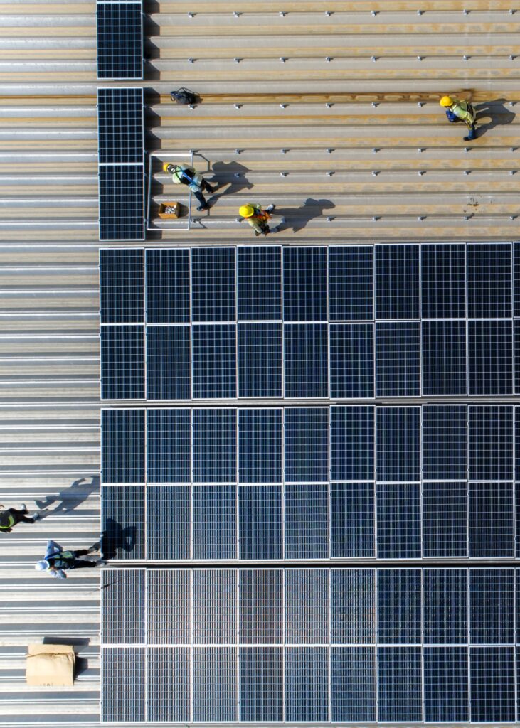 Workers installing solar panels on roof of a business